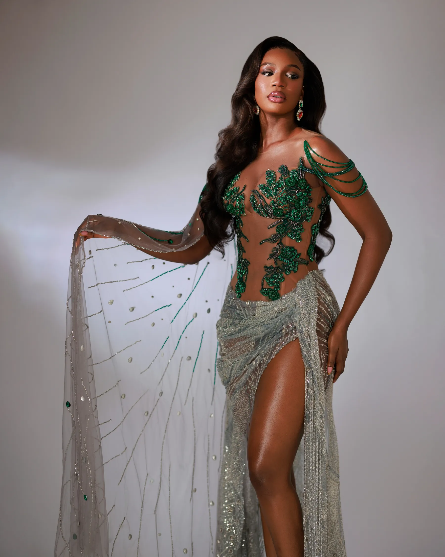 The beaded tulle cape of the Jiofit Miss Universe Nigeria gown, held out to show the emerald and crystal drops